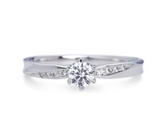 a white gold engagement ring with diamonds on the band and a round brilliant cut diamond in the center