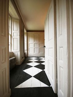 an open door leading to another room with black and white flooring