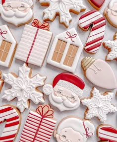 christmas cookies decorated like santa claus and other holiday treats on a white tablecloth with red and gold decorations