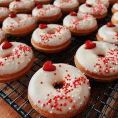 there are many donuts with white frosting and red sprinkles on them