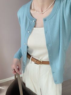 a woman holding a pair of scissors in her right hand and wearing a blue cardigan