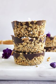 three granola cups stacked on top of each other with purple flowers in the background