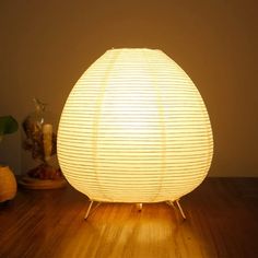 a white lamp sitting on top of a wooden table next to a potted plant