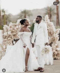 a bride and groom standing in front of an outdoor wedding ceremony area with white flowers