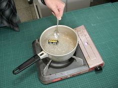 a person stirring something in a pot on top of a stove with a measuring scale