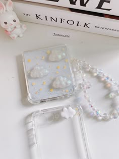 the phone case is made out of clear plastic and has white pearls on it, along with a beaded necklace