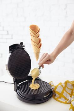 a waffle being drizzled with peanut butter on top of an electric waffle maker