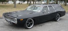 an old black station wagon is parked on the street