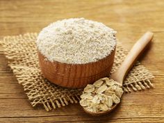 a wooden spoon sitting on top of a table next to a bowl filled with oatmeal