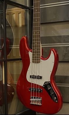 a red bass guitar sitting on top of a display case