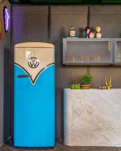 a blue refrigerator sitting next to a white counter in a room with shelves on the wall