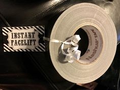 a roll of toilet paper sitting on top of a black leather bag next to a tag that says instant facelift