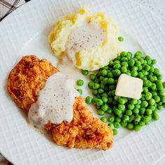 a white plate topped with chicken, mashed potatoes and peas