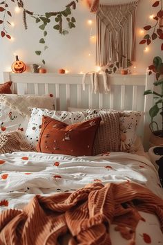 a white bed topped with lots of pillows next to a wall covered in pumpkins