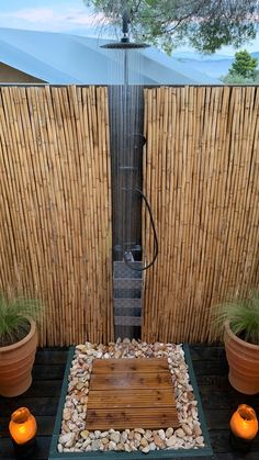 an outdoor shower in the middle of a wooden deck with two potted plants next to it