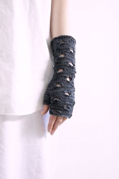 a woman's arm is wrapped in a knitted glove with holes on it