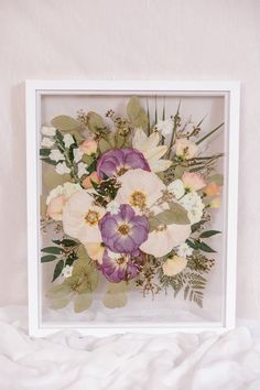 an arrangement of flowers in a white frame