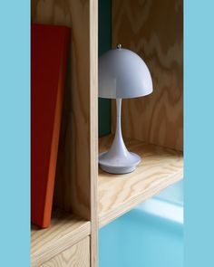 a white lamp sitting on top of a wooden shelf