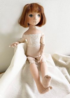 a doll sitting on top of a white sheet