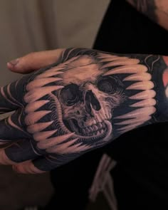 a person with a tattoo on their arm and hand holding a skull in the shape of a bear