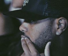 a close up of a person wearing a hat and holding his hand to his face