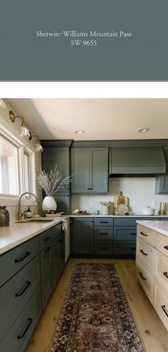 a large rug in the middle of a kitchen with gray cabinets and white counter tops