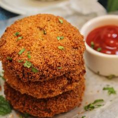 three fried food items are stacked on top of each other next to a small bowl of ketchup