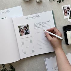 a person holding a pen and writing on an open book with photos in the pages