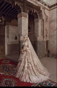 a woman in a wedding dress standing next to a rug with an ornate design on it