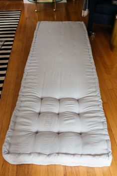 a mattress is laying on the floor in front of a black and white striped rug