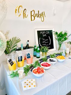 a table topped with bowls of fruit and drinks next to a sign that says oh baby