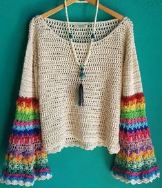 a white sweater with multicolored crochet on it and a tassel