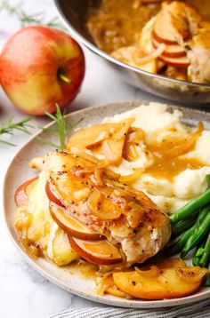 a white plate topped with mashed potatoes and green beans next to two silver pans filled with food