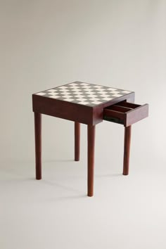 a wooden table with a checkerboard design on the top and drawer underneath it