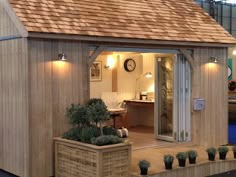 a small wooden house sitting on top of a floor next to potted planters