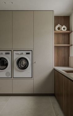 a washer and dryer in a room with shelves on the wall behind them