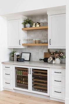 a kitchen with white cabinets and shelves filled with wine glasses on top of the counter