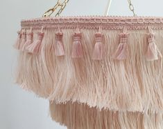 a pink chandelier with tassels hanging from it's side on a white wall