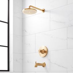 the shower head and hand shower faucet are shown in this white bathroom with gold fixtures