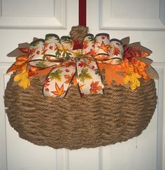 a wreath hanging on the front door decorated with fall leaves and ribbons, tied in twine