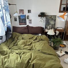 an unmade bed sitting in a bedroom next to a lamp and pictures on the wall