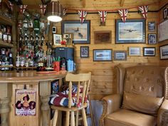 a bar with two chairs and pictures on the wall above it, along with other memorabilia