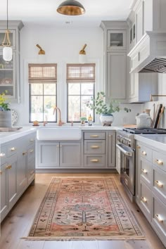 a kitchen with gray cabinets and white counter tops, an area rug on the floor