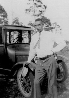 a man standing in front of an old car