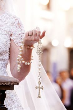 a woman in a wedding dress holding a rosary