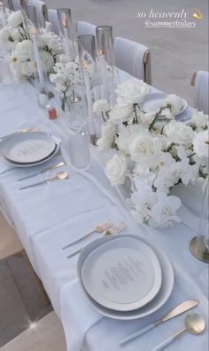 the table is set with white flowers and silverware