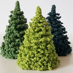 three crocheted christmas trees sitting next to each other