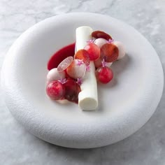 a white plate topped with fruit and cheese on top of a marble countertop covered in red sauce