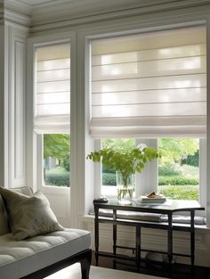 a living room filled with furniture and windows covered in white roman shade blinds on top of them