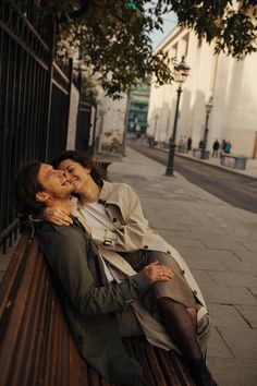 two women are sitting on a bench and one is kissing the other's cheek